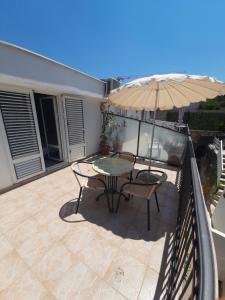 a patio with a table and an umbrella on a balcony at Apartments Mitrovići Miločer in Sveti Stefan