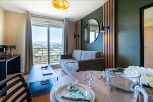 Nemea Appart Hotel Green Side Biot Sophia Antipolis في بيوت: غرفة معيشة مع طاولة وأريكة