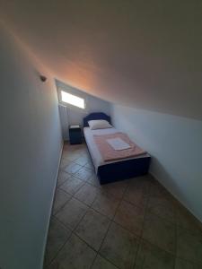 a small bedroom with a bed and a window at Apartments Mitrovići Miločer in Sveti Stefan