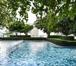 una piscina con árboles y un edificio de fondo en LUCKY HOME SAMRONG en Bangna