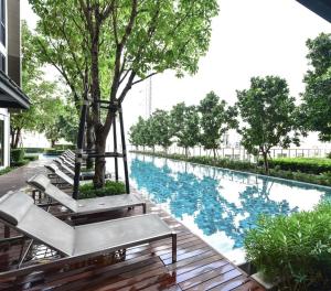 una piscina con panchine e alberi in un edificio di LUCKY HOME SAMRONG a Bang Na