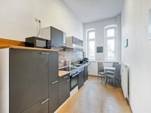 Una cocina con electrodomésticos de acero inoxidable y una mesa. en Ferienwohnung Villa Nieske - Jugendstil Denkmal, free WLAN & Parken, Self Check-In, Smart-TV, en Herzberg