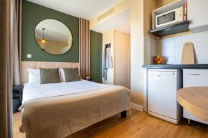 ein kleines Schlafzimmer mit einem Bett und einem Spiegel in der Unterkunft Nemea Appart Hotel Green Side Biot Sophia Antipolis in Biot