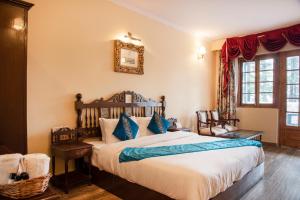 a bedroom with a large bed with blue pillows at Shimla British Resort in Shimla