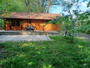 una cabaña de madera con dos personas delante de ella en Knusse blokhut op groot en groen perceel @ Veluwe, en Epe