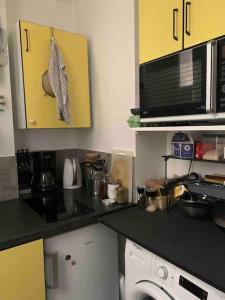 een keuken met een zwart aanrecht en een magnetron bij Appartement de charme à proximité des puces in Saint-Ouen