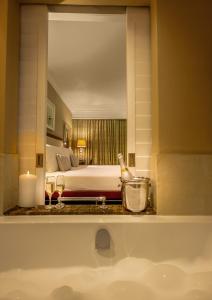 a bathroom with a bed and a sink with a mirror at Hemingways Hotel in East London