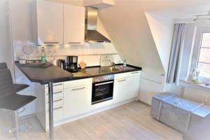 a kitchen with white cabinets and a stove top oven at An de Warft Appartement 10 Schatz am Deich in Büsum +20 photos