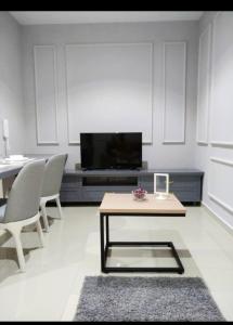 uma sala de estar com uma televisão e uma mesa e cadeiras em I City Suite Free Wifi em Shah Alam