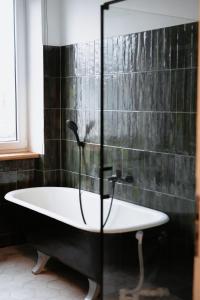 uma banheira na casa de banho com azulejos pretos em Vintage apartment Ranne em Riga
