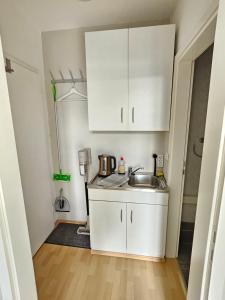 una pequeña cocina con armarios blancos y fregadero en Stadtapartment HEF en Bad Hersfeld