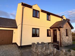 a yellow house with a garage in front of it at 4 Bed Farmhouse - Pets - Garden - Parking in Beaumaris +17 photos