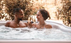 Un uomo e una donna in una vasca da bagno con champagne di Les Violettes Hotel & Spa a Jungholtz