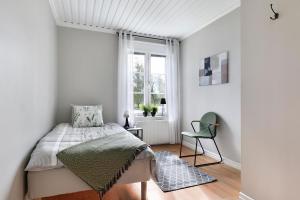 a bedroom with a bed and a chair and a window at Guestly Homes - 4BR Charming Apartment in Roknäs