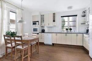 - une cuisine avec des placards blancs, une table et des chaises dans l'établissement Guestly Homes - 4BR Charming Apartment, à Roknäs