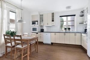 a kitchen with white cabinets and a table and chairs at Guestly Homes - 4BR Charming Apartment in Roknäs