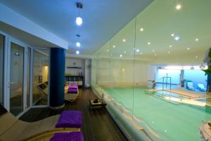 a swimming pool with purple chairs in a building at Hotel Royal in Riva del Garda