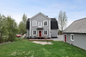 une maison grise avec une porte rouge et une cour dans l'établissement Guestly Homes - 4BR Charming Apartment, à Roknäs