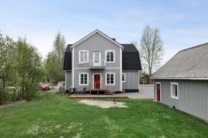 a gray house with a red door and a yard at Guestly Homes - 4BR Charming Apartment in Roknäs