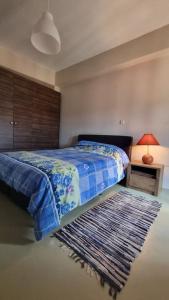 a bedroom with a bed with a blue blanket and a rug at The Black Chestnut in Áyios Nikólaos