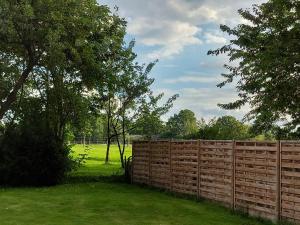 a fence in a yard with trees and a field at Ferienwohnung am Wald 