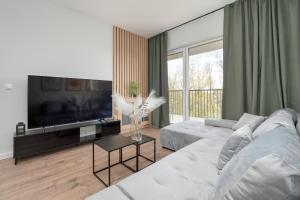 a living room with a white couch and a flat screen tv at Wieniawskiego Apartment with Balcony Stacja Łódź Estate by Renters in Łódź