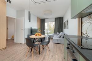 a kitchen and living room with a table and chairs at Wieniawskiego Apartment with Balcony Stacja Łódź Estate by Renters in Łódź