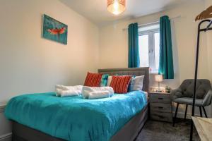 1 dormitorio con cama con sábanas azules y silla en Admirals House - Cosy house in quiet cul-de-sac en Gaywood