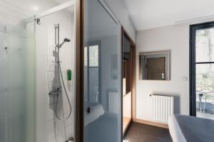 uma casa de banho com um chuveiro e uma porta de vidro em Hôtel du Château Dinan - Originals Boutique em Dinan