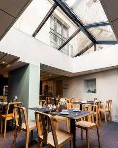 a dining room with tables and chairs and a large skylight at Hôtel du Château Dinan - Originals Boutique in Dinan