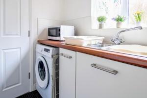 a kitchen with a sink and a washing machine at Admirals House - Cosy house in quiet cul-de-sac in Gaywood