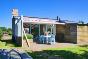 a house with a table and chairs on a patio at Previnaireweg 32 in Callantsoog