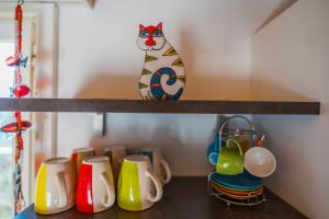 a shelf with cups and a cat on it at Naturoase Säntisblick-Auszeit am Wald und Bach in Kradolf