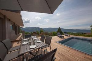a patio with a table and chairs next to a swimming pool at Appartement UBAC in Rovagny