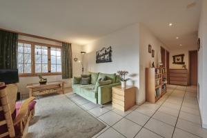 a living room with a green couch and a table at Chalet Panorama 1 in Wengen +26 photos