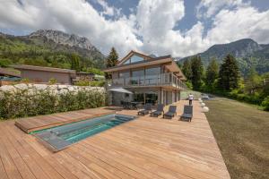 a house with a wooden deck and a swimming pool at Appartement Adret in Rovagny