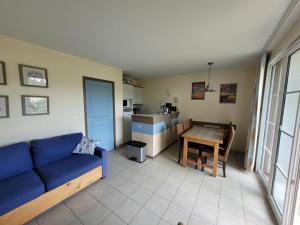 ein Wohnzimmer mit einem blauen Sofa und einem Tisch in der Unterkunft Villa Fort-Mahon-Plage, 3 pièces, 4 personnes - FR-1-730-37 in Fort-Mahon-Plage