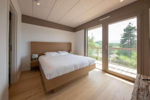 a bedroom with a large bed and a large window at Lot appartements Adret et Ubac in Rovagny