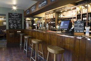 un bar con taburetes frente a un mostrador en The Wheatsheaf Inn en Kendal