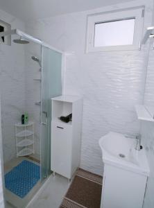 a white bathroom with a shower and a sink at Carla Apartment Opuzen Modern Oasis and Comfort in Opuzen