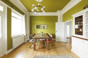 ein Esszimmer mit grünen Wänden und einem Tisch und Stühlen in der Unterkunft Ferienwohnungen in der Villa Lindenallee 9 in Malente