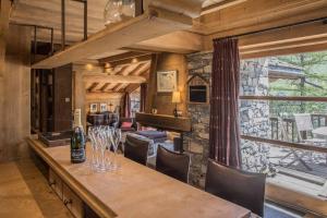 un comedor con una mesa con copas de vino. en Val d’Isère - Extraordinaire Chalet Montana avec piscine sur la piste Olympique de Belevarde., en Val dʼIsère