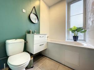 a bathroom with a toilet and a tub and a window at Le Green Lodge in Nevers