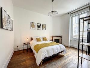 a white bedroom with a bed and a fireplace at Le Green Lodge in Nevers
