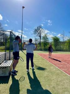 Eine Gruppe von Menschen steht auf einem Tennisplatz. in der Unterkunft Tiny Botanic House in Tzummarum + 37 Fotos