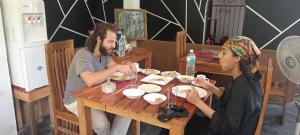 Un uomo e una donna seduti a tavola mangiando cibo di Freedom Safari Cottage a Udawalawe