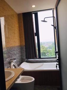 ein Bad mit einer Badewanne, einem WC und einem Fenster in der Unterkunft Hotel Stylish Binh Long in Thanh Bình