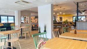 un restaurante con mesas y sillas de madera y un bar en Campanile St Etienne Centre - Villars La Terrasse, en Villars