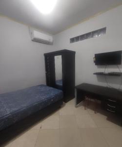 a room with a bed and a desk and a television at SPOT ON 93853 Budi Residence 2 in Bekasi