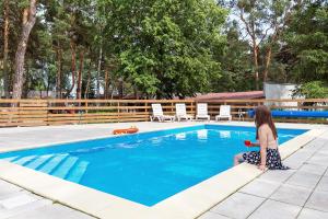 a woman sitting on the edge of a swimming pool at Brzozowa Zatoka Brenno in Brenno